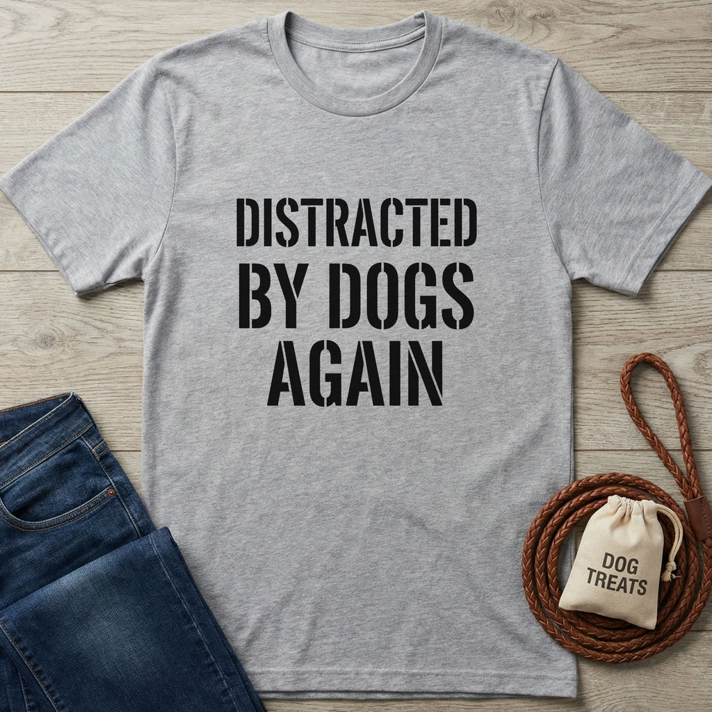 Light grey Gildan Softstyle t-shirt with "DISTRACTED BY DOGS AGAIN" in black text, next to jeans and dog treats.