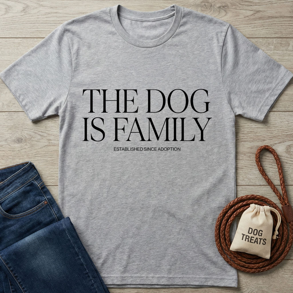 Light grey Gildan Softstyle® t-shirt with "THE DOG IS FAMILY" text, next to jeans and dog treats.