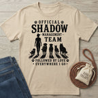 Beige cotton t-shirt with "Official Shadow Management Team" graphic featuring a person and five dogs.