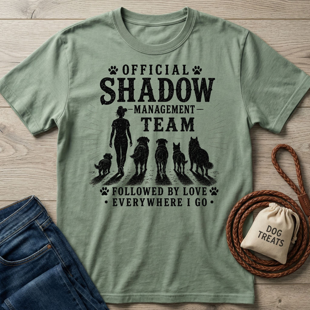 Sage green cotton t-shirt with "Official Shadow Management Team" graphic featuring a person and five dogs.