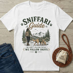 White crewneck t-shirt featuring a hiker and dog graphic with Sniffari Guide text on a wooden background.