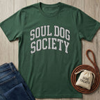 Dark green "Soul Dog Society" t-shirt with white collegiate text, folded jeans, and a treat bag.