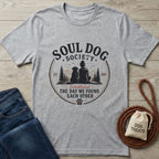 Light grey Gildan Softstyle® t-shirt with "Soul Dog Society" graphic of a person and dog, beside jeans and dog treats.