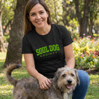 Woman in a black Soul Dog Society t-shirt with green text, petting a rescue dog outdoors.