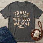 Dark gray "Trails Are Better With Dogs" t-shirt with a mountain, trees, and dog design, next to jeans, a leash, and dog treats.
