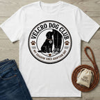 White crewneck t-shirt featuring a black Velcro Dog Club graphic of a dog sitting by a person's legs.