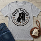 Grey crewneck t-shirt featuring a circular Velcro Dog Club graphic with a black dog sitting by a person's legs.