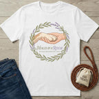 White cotton t-shirt with "Healed By A Rescue" graphic of a human hand holding a dog paw, encircled by lavender.