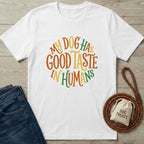 White Gildan Softstyle t-shirt with "My Dog Has Good Taste In Humans" in orange, yellow, and green.