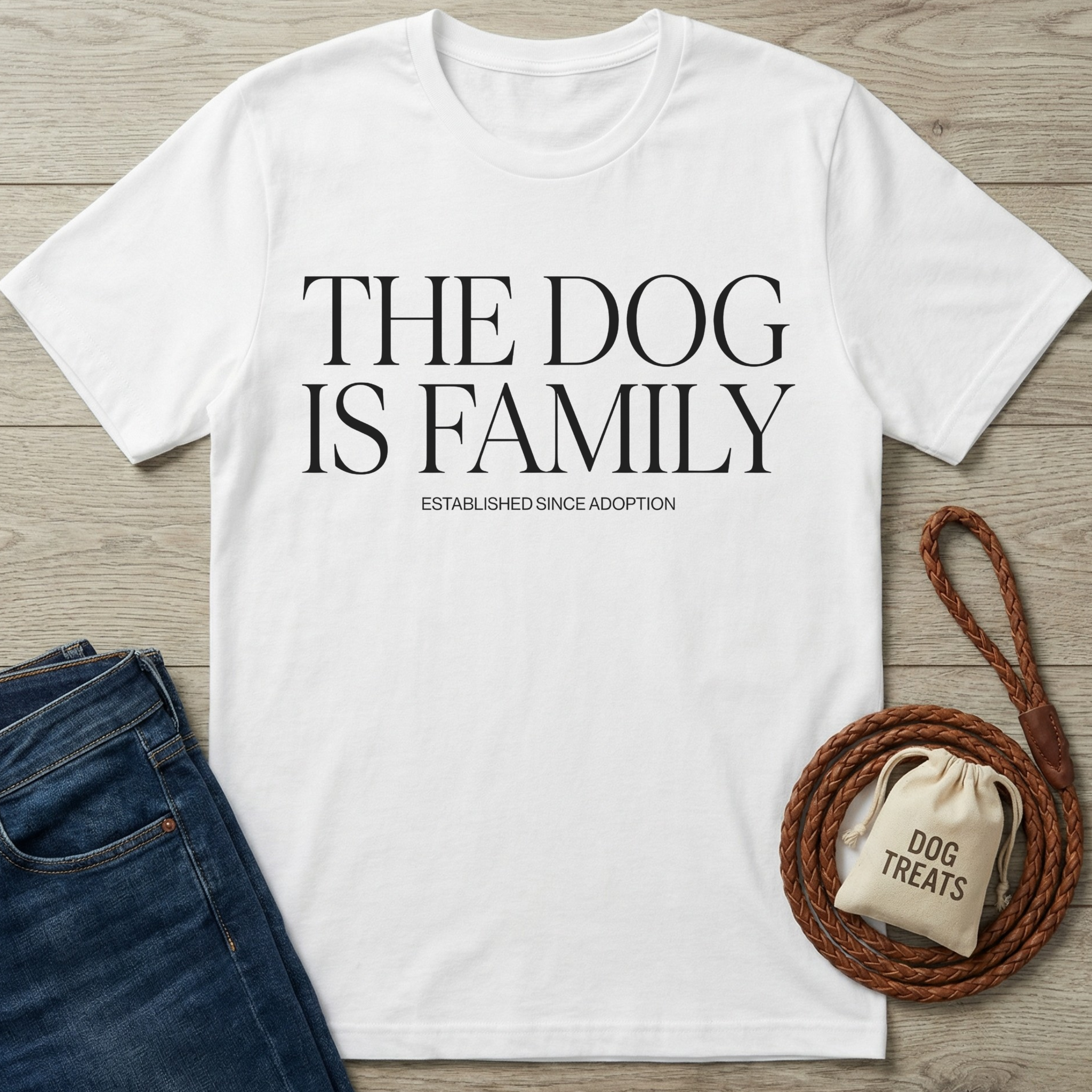 White cotton t-shirt with "THE DOG IS FAMILY" text, blue jeans, and a braided leather leash with a treat bag.
