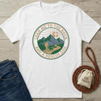 White cotton t-shirt with "Lead Me To The Rock And A Rescue Dog" graphic featuring mountains, sun, hiker, and dog.