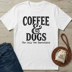 White cotton t-shirt with "Coffee & Dogs The Only Two Essentials" text, next to jeans and dog treats.