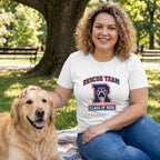 Woman in a white "Rescue Team R Class of 2026" tee petting a golden retriever in a park.
