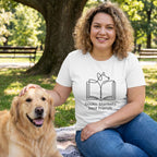Woman in a white "Books Blankets Best Friends" tee petting a golden retriever in a park.