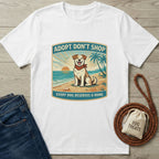 White Gildan Softstyle® t-shirt with "Adopt Don't Shop" beach dog graphic, paired with jeans and dog treats.
