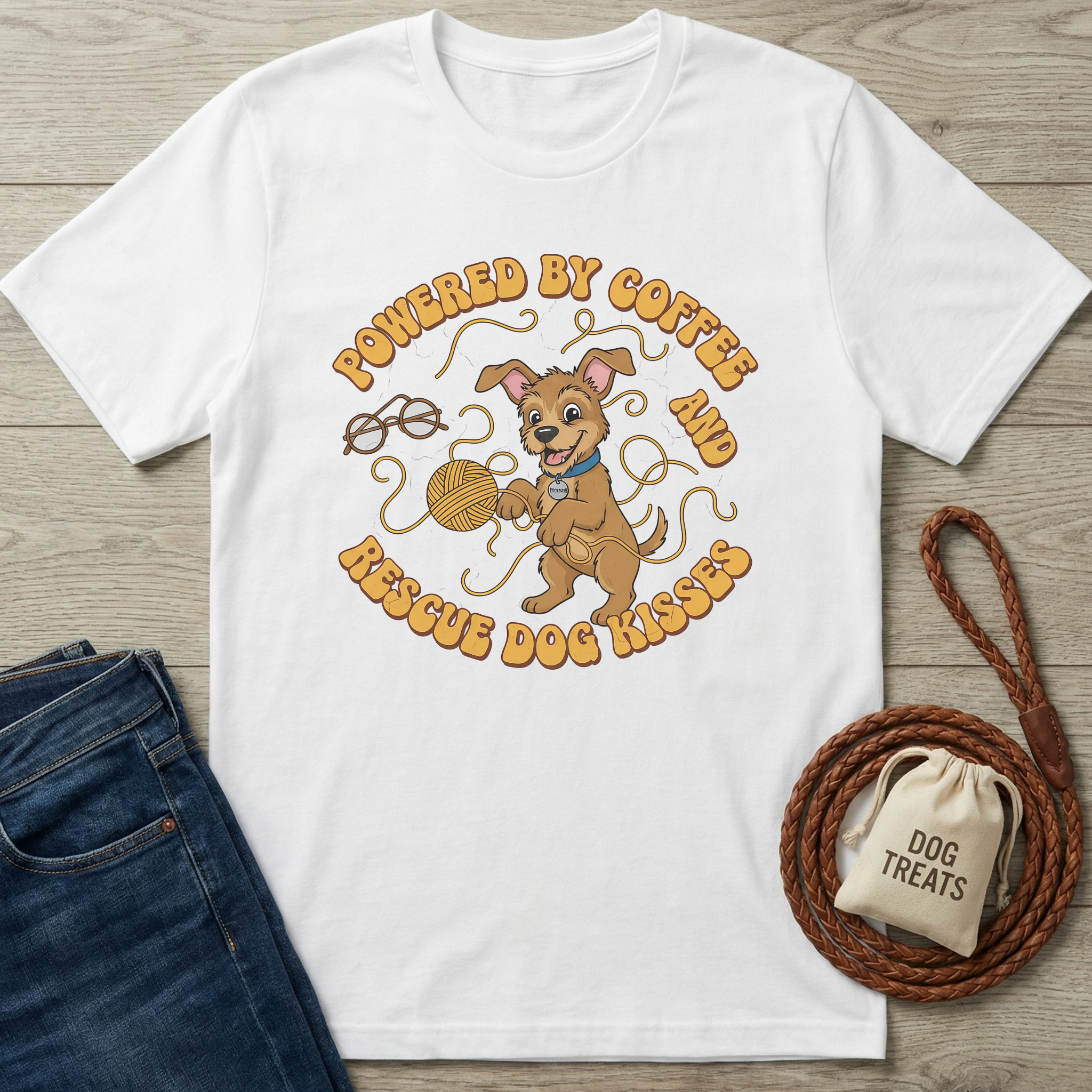 White cotton t-shirt with a cartoon dog playing with yarn and "Powered by Coffee & Rescue Dog Kisses" text.