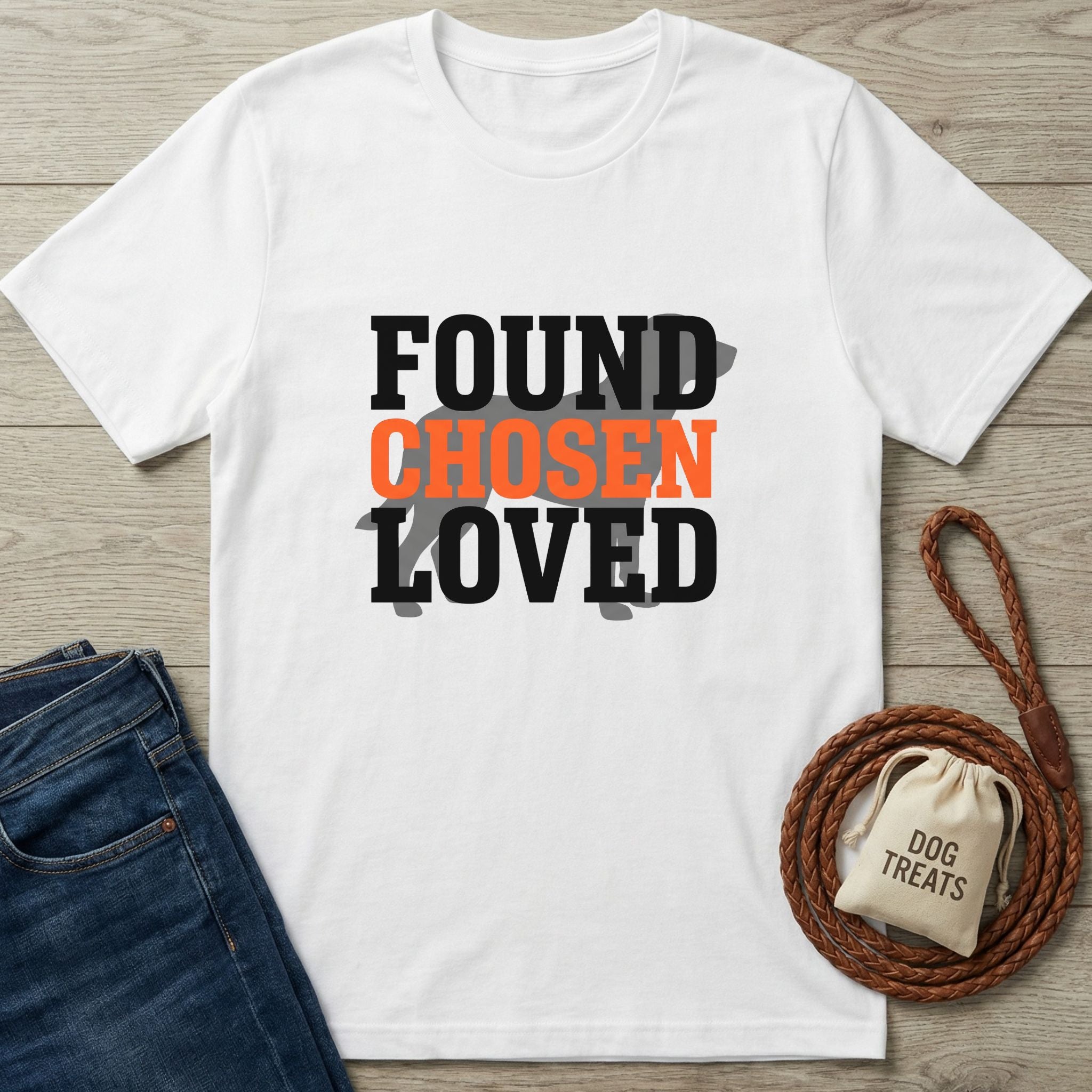 White Gildan Softstyle t-shirt with "FOUND CHOSEN LOVED" text and a dog silhouette, beside jeans and a leash.