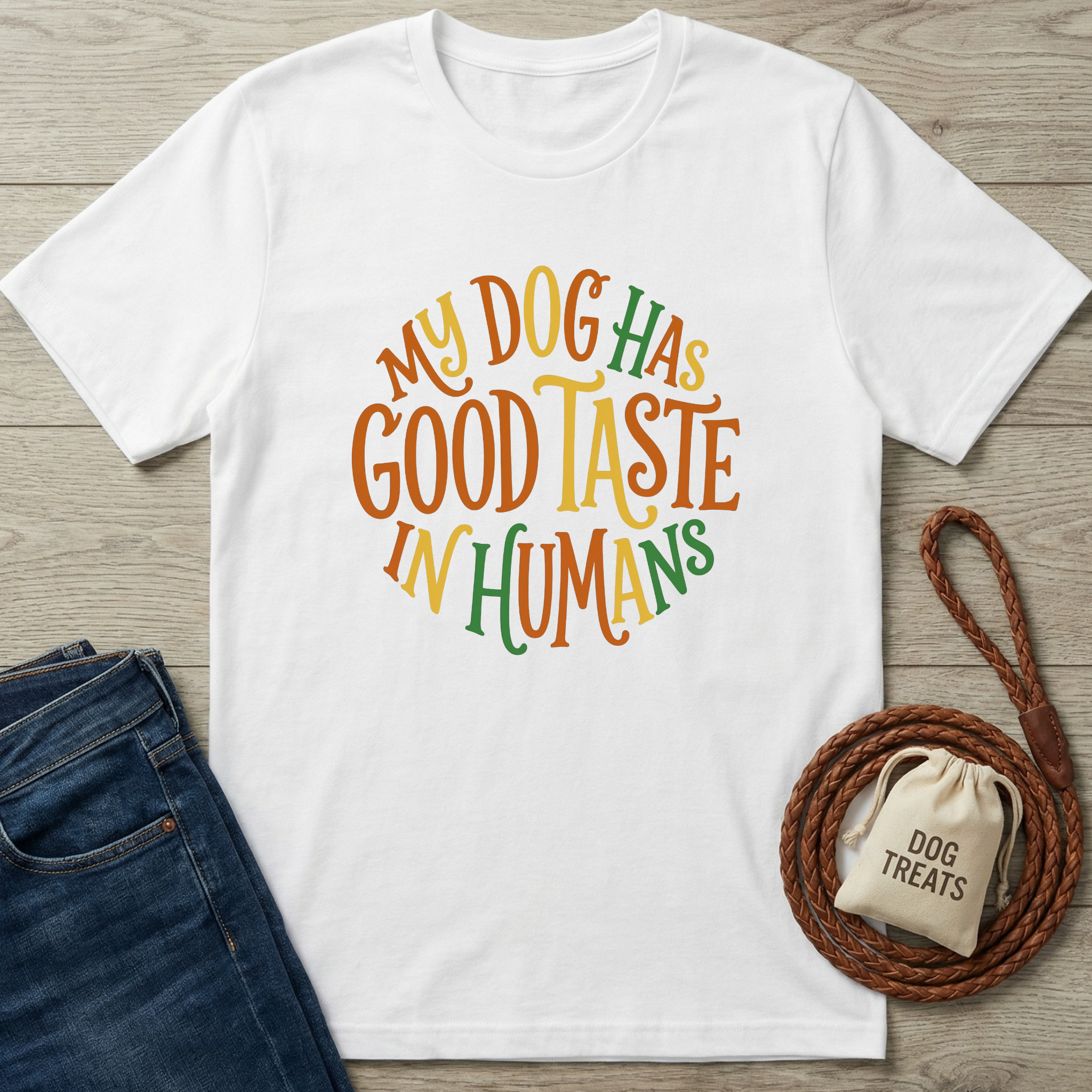 White cotton t-shirt with "My Dog Has Good Taste In Humans" in orange, yellow, and green text.